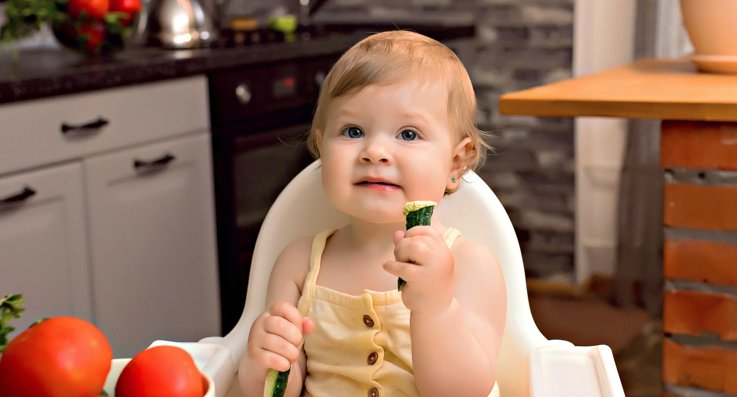 10 month old dipping cucumber into hummus