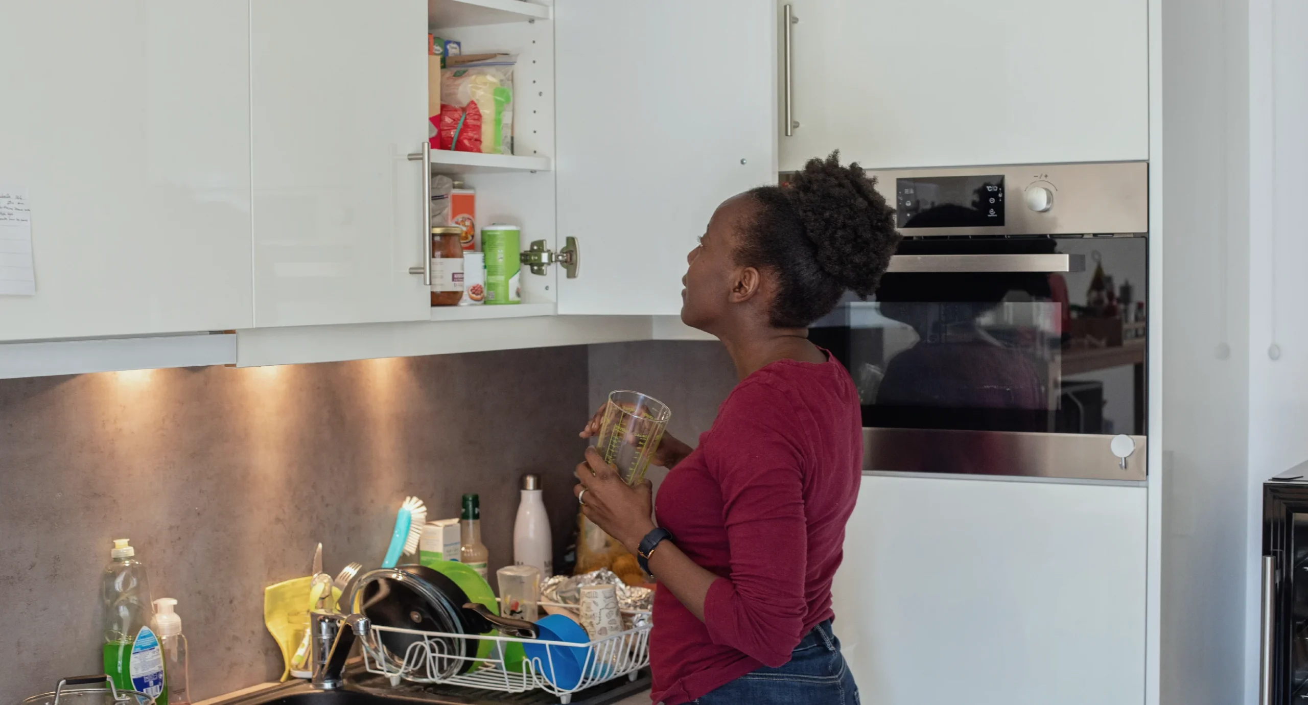 parent opening their kitchen cupboard looking at the different foods inside.